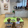 Kleine Kinder sitzen an einem Tisch und essen kleingeschnittenes Obst