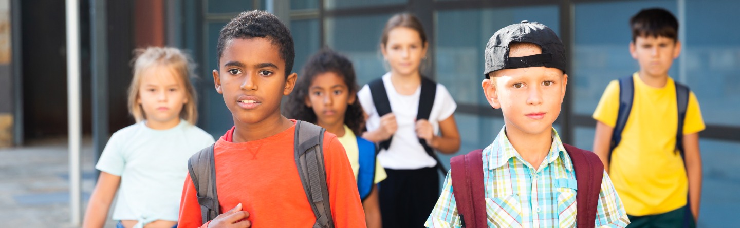 Header: Einige junge Schülerinnen und Schüler laufen gerade aus ihrer Schule raus. 