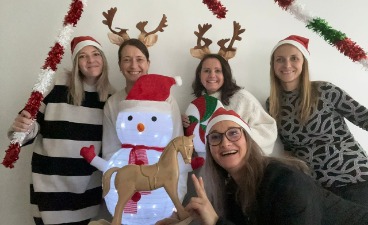 Frohe Weihnachten: Unsere proSenio-Kolleginnen Aileen, Jasmin, Claudia, Annika und Conny posieren in Weihnachtskostümen mit einem selbstgebastelten Schneemann vor einer weißen Wand.