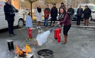 Ausbildung zum Brandschutzhelfer: Eine Frau löscht mit einem Handfeuerlöscher einen Ölbrand