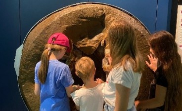 Vier Kinder stehen vor einem Exponat in Museum