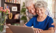 Älteres Ehepaar vor einem Notebook, lächelnd