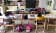 Kinder sitzen an Schultischen in einem Klassenzimmer