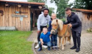 News- Bild: Zwei Kinder und zwei Erwachsene posieren mit einem Pony