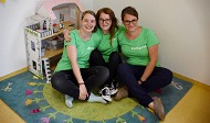 News- Bild: Drei Mitarbeiterinnen posieren auf dem Boden sitzend