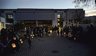 News- Bild: Mehrere Personen posieren während Abenddämmerung mit leuchtenden Laternen vor einem Gebäude