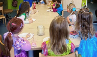 News- Bild: Kostümierte Kinder sitzen um einen Tisch